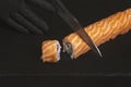 Preparing sushi at home - close up of hands cutting a Roll