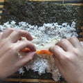 Making Sushi Rolls at Home: Female Hands Put Salmon Fish Strips on Cream Cheese, Rice and Nori Seaweed Sheet Placed on a Bamboo Royalty Free Stock Photo