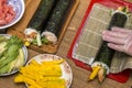 Making sushi and rolls at home. Plates with ingredients for traditional Japanese food and sushi rolls on wooden board on kitchen Royalty Free Stock Photo