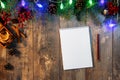 Making a to-do list or plan for next year. Christmas tree branch and lights on wooden background. writing a letter to Santa
