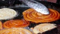 Making of traditional street food jilebi ,frying deep of maida or plain flour batter before soaking in sugary syrup