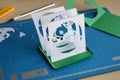 Making tunnelbook. 3D greeting card Spring. Artwork equipment and tools for paper cut - cutting knife, sharp box cutter, blue Royalty Free Stock Photo