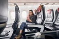 Making video connection. Young woman in casual clothes sits on the passenger seat in the plane