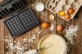 Making waffles at home - waffle iron, batter in bowl and ingredients - milk, eggs and flour. Royalty Free Stock Photo