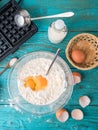 Making waffles at home - waffle iron, batter in bowl and ingredients - milk, eggs and flour. Royalty Free Stock Photo