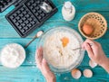 Making waffles at home - waffle iron, batter in bowl and ingredients - milk, eggs and flour. Royalty Free Stock Photo