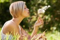 Making a wish. An attractive young woman blowing on a dandelion in an open field. Royalty Free Stock Photo