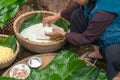 Making wrapping Chung Cake, the Vietnamese lunar new year Tet food outdoor with old woman hands and ingredients. Closed-up.