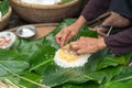 Making wrapping Chung Cake, the Vietnamese lunar new year Tet food outdoor with old woman hands and ingredients. Closed-up.