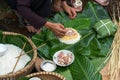 Making wrapping Chung Cake, the Vietnamese lunar new year Tet food outdoor with old woman hands and ingredients. Closed-up.