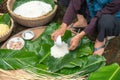 Making wrapping Chung Cake, the Vietnamese lunar new year Tet food outdoor with old woman hands and ingredients. Closed-up.