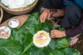 Making wrapping Chung Cake, the Vietnamese lunar new year Tet food outdoor with old woman hands and ingredients. Closed-up.