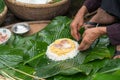 Making wrapping Chung Cake, the Vietnamese lunar new year Tet food outdoor with old woman hands and ingredients. Closed-up.