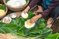 Making wrapping Chung Cake, the Vietnamese lunar new year Tet food outdoor with old woman hands and ingredients. Closed-up.