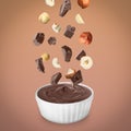 Making yummy chocolate paste. Hazelnuts and pieces of chocolate falling into bowl on light brown background Royalty Free Stock Photo