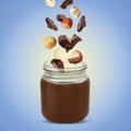 Making yummy chocolate paste. Hazelnuts and pieces of chocolate falling into jar on light blue background Royalty Free Stock Photo