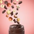 Making yummy chocolate paste. Hazelnuts and pieces of chocolate falling into jar on pale red Royalty Free Stock Photo