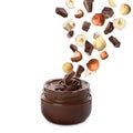 Making yummy chocolate paste. Hazelnuts and pieces of chocolate falling into jar on white background Royalty Free Stock Photo