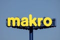 Makro Cash and Carry logo with a blue sky background.