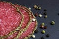 Makro closeup of slices french fresh salami with mixed pepper crust with peppercorns on black slate stone board