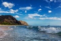 Makua beach view of the wave with beatiful mountains and a sailboat in the background, Oahu island