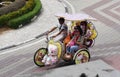 Malacca, Malaysia--February 2018: Downward view of a colorful trishaw with a couple of women riding along the brick-paved Dutch