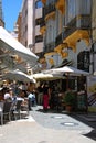 People relaxing at pavement cafes in a side street, Malaga, Spain.