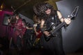 Bearded man headbanging and playing guitar next to a female vocalist and a long-haired blond rocker