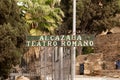 Malaga, Spain- 26-01-2024: Vintage metal sign 'ALCAZABA TEATRO ROMANO' among lush trees. The Roman Theatre is