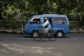 A city transportation that is empty of passengers and old cyclists crosses the corner in front