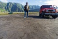 Malang, Indonesia - 25 March 2018 : Photo of an adult asian man pose next to a red jeep truck at Mount Bromo