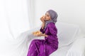 Malay Asian girl celebrates end of Ramadan, in purple kebaya dress, and holding bahulu food Royalty Free Stock Photo