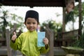 A Malay boy in Malay traditional cloth showing his happy reaction after received money pocket during Eid Fitri or Hari Raya celebr Royalty Free Stock Photo