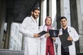 Malay doctors wearing white coats and scrubs, posing together, standing outside the hospital Royalty Free Stock Photo