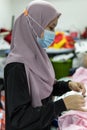 Malay Muslim Female Worker with protective face mask and maintaining social distancing while working in Embroidery Textile Garment