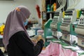 Malay Muslim Female Worker with protective face mask and maintaining social distancing while working in Embroidery Textile Garment