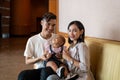 Malay Young Couple with One Year Old Child Daughter, sitting on brown sofa