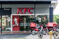 Fast food restaurant KFC view from the street, motorbike delivery service with box refrigerators parked at entrance.