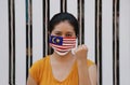 Malaysia flag on hygienic mask. Masked Asian woman prevent germs. concept of Tiny Particle protection or virus corona or Covid 19 Royalty Free Stock Photo