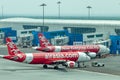 Airplane by Airasia airline is towed to a parking lot with aircraft towing tractors.