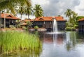 Small pond with fountain among a beautiful garden with tall palm trees Royalty Free Stock Photo