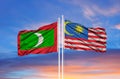 Malaysia and Maldives flag waving in the wind against white cloudy blue sky together. Diplomacy concept, international relations