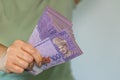 Malaysia money, A woman holds a large stack of 100 Malaysian ringgit banknotes in her hand, close up