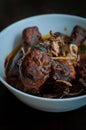 Malaysian dish of Ayam Masak Kicap or deep fried chicken in black soy gravy in a white bowl