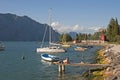 A topless Italian man lying at the edge of small pier enjoying mountain view with yacht boats at Malcesine town, Lake Garda, Italy Royalty Free Stock Photo