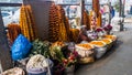 An Indian flower seller sitting on the pavement at his stall on the market streets of