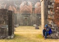 A man sitting beneath the ruins of the ancient walls of the Adina Masjid in the village