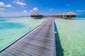 Maldives island luxury water villas resort and wooden pier. Beautiful sky and clouds and luxury beach background Royalty Free Stock Photo