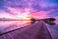 Maldives island sunset landscape. Colorful clouds and sky with luxury water villas and long wooden pier