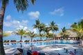 Maldives - January 17, 2013: People rest and swim in water pool by tropical ocean beach with coconut palm trees and lounge chairs.